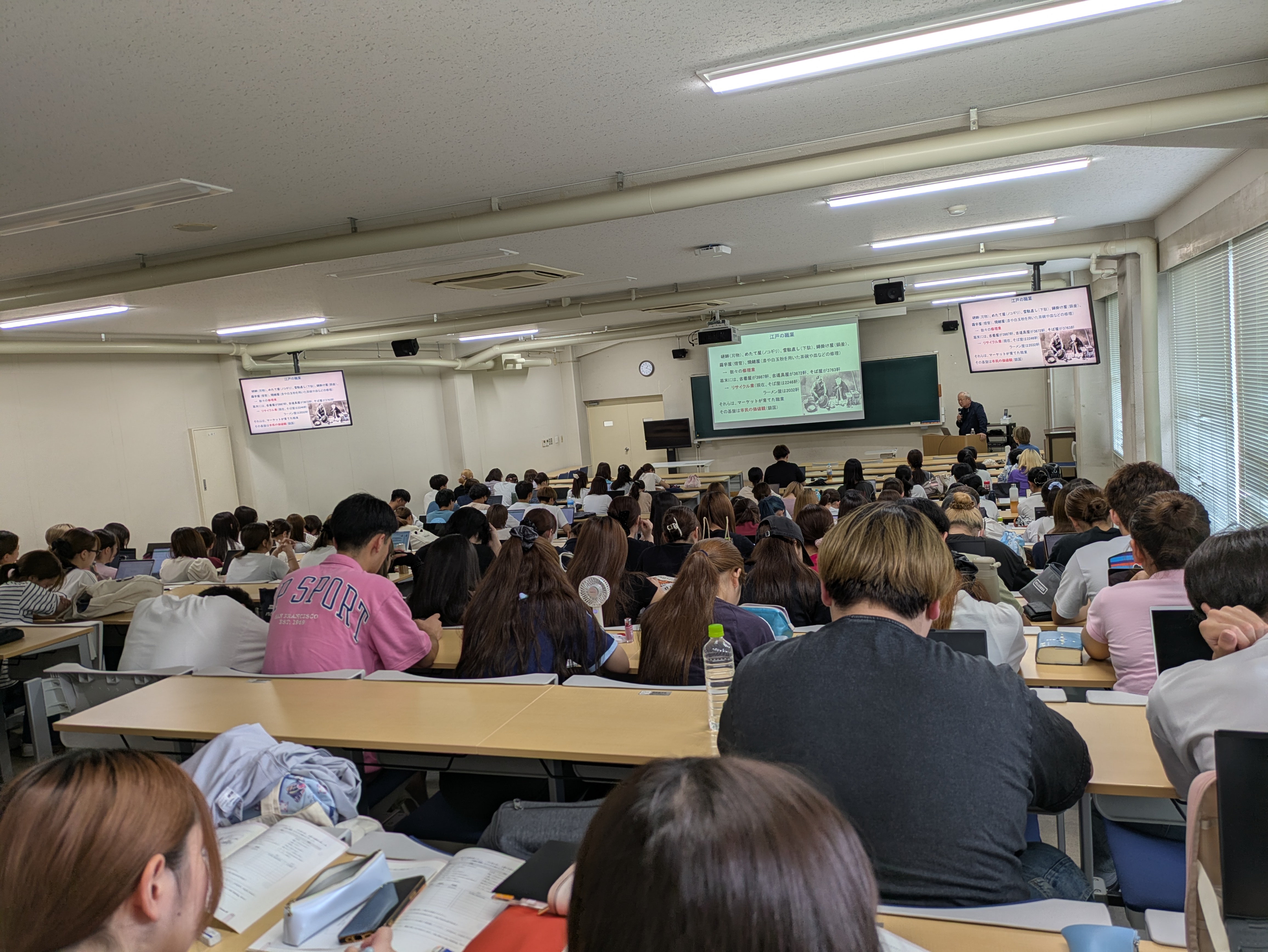 大学の講義室で映像を投影しながら話す渋沢寿一
